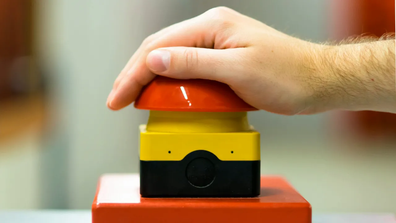 Hand pressing a large red and yellow classroom buzzer button