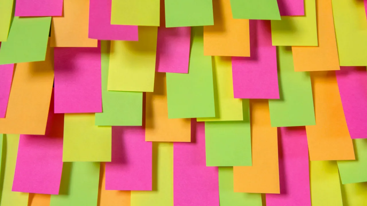 Close-up of colourful Post‑it notes (pink, green, orange) arranged on a surface for classroom review activities