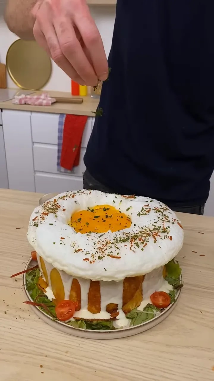 Grand croque-monsieur rond recouvert de blanc crémeux avec jaune au centre