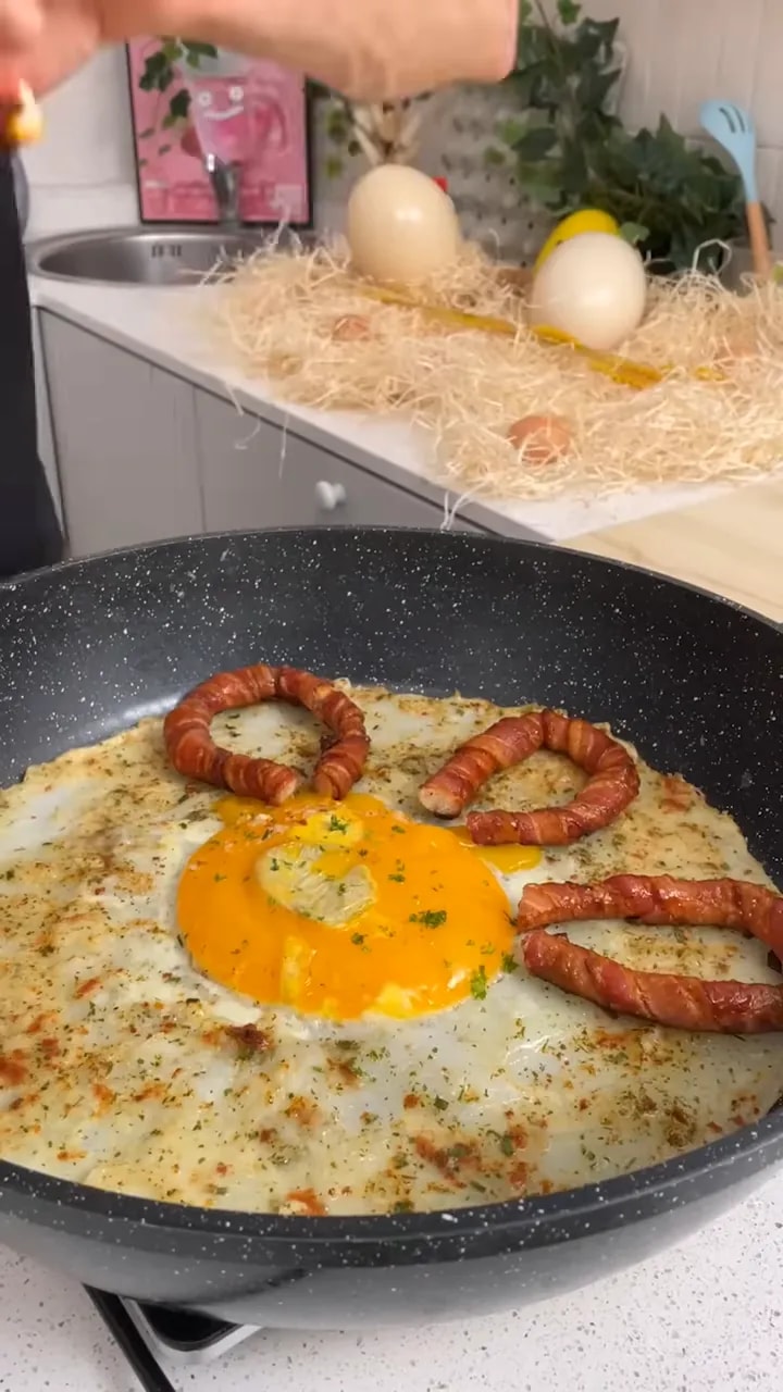 Grand œuf au plat avec jaune orange au centre et anneaux de saucisse